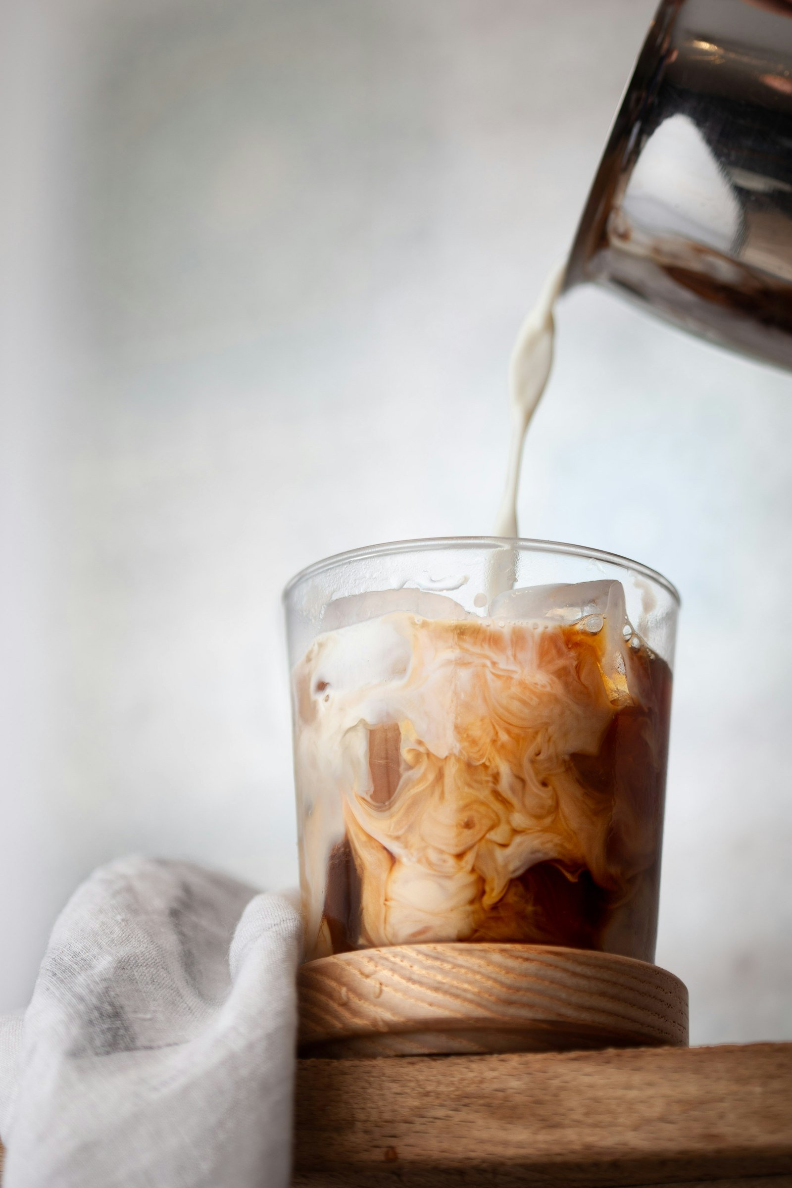 Milk being poured over iced coffee