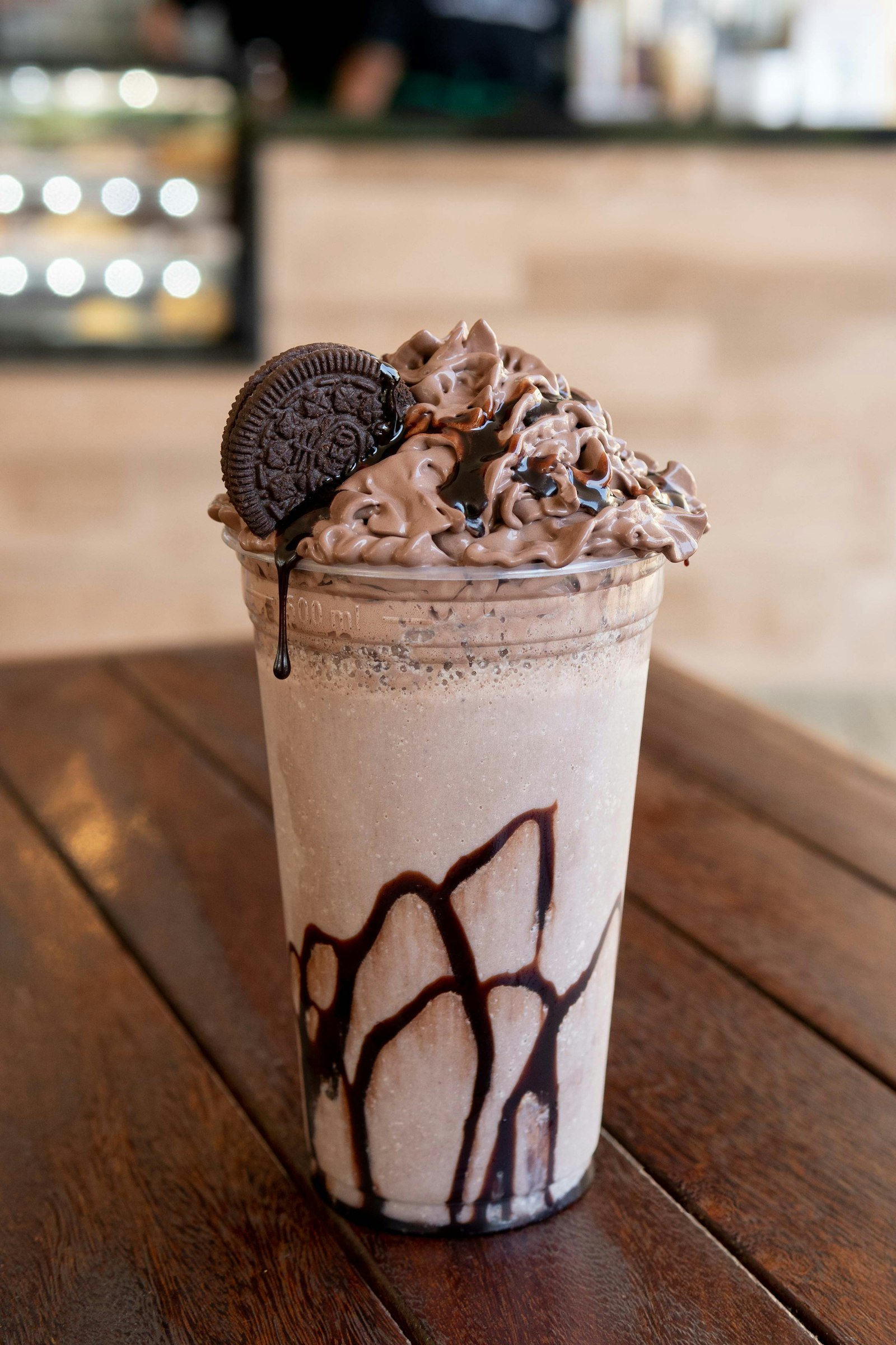 Tall glass of chocolate frappe topped with whipped cream and a cookie at Cafe Brew Vibe